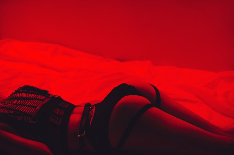 Backside of woman in BDSM gear with red lighting