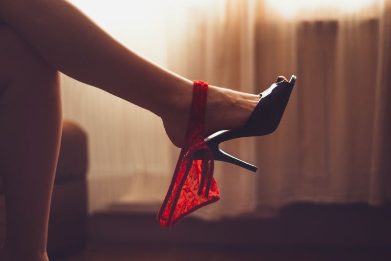 Pieds de femme en talons noirs avec culotte pendante