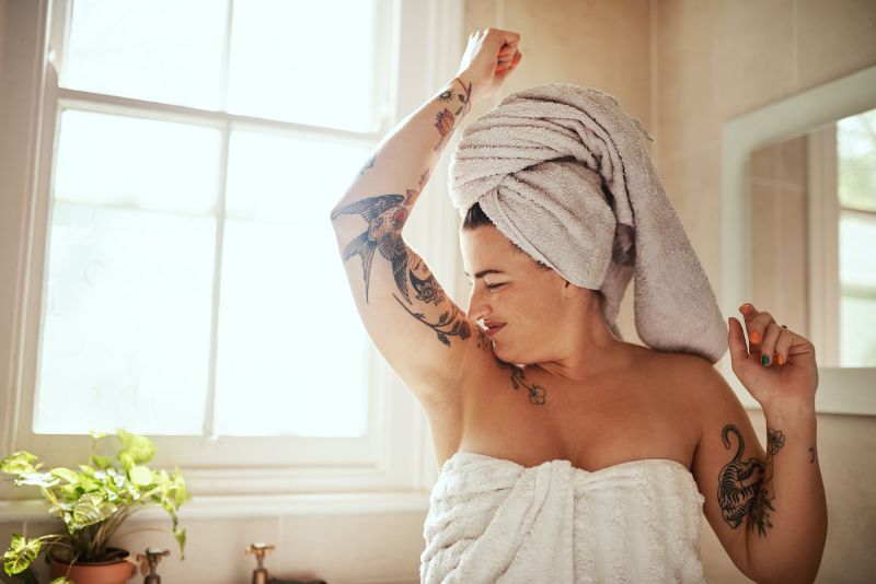 woman in towel smelling her own armpit