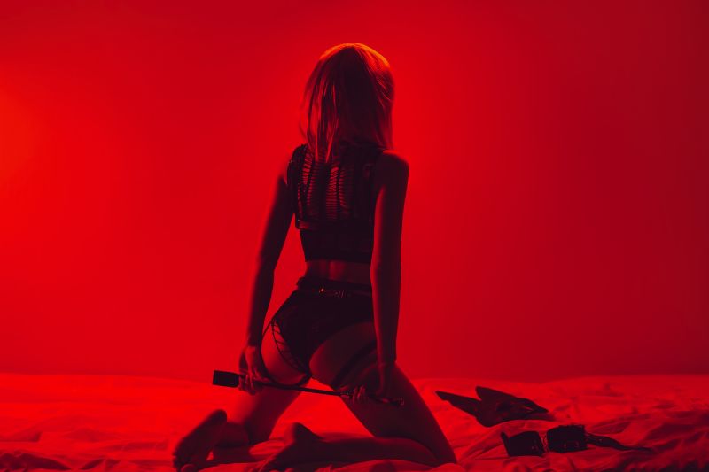 Woman in underwear with BDSM whip red room