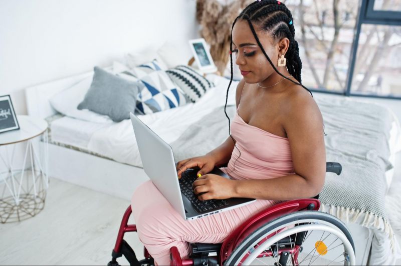 Woman in wheelchair on laptop at home