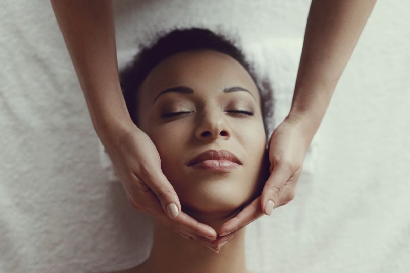 Femme allongée recevant un massage du visage