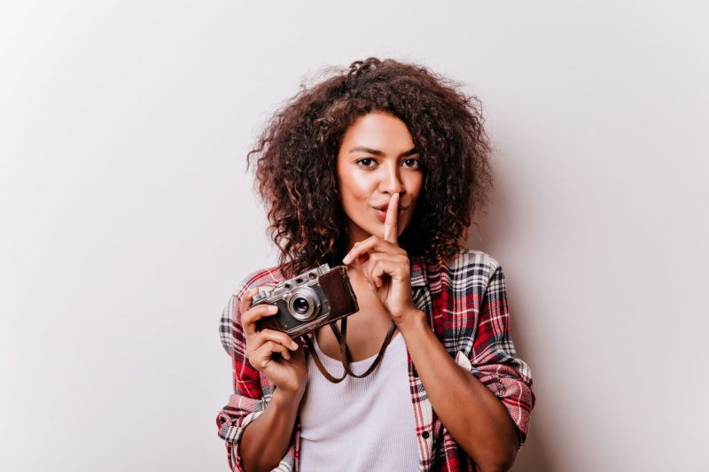 Woman making sh sign and holding camera