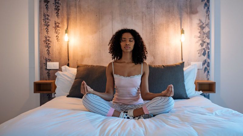 Woman meditating at home on bed