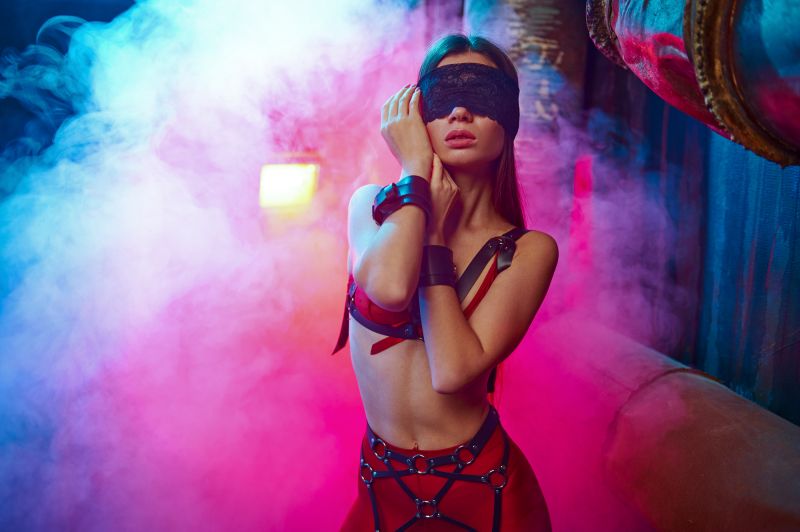 Femme pose en costume BDSM lingerie et harnais avec les yeux bandés