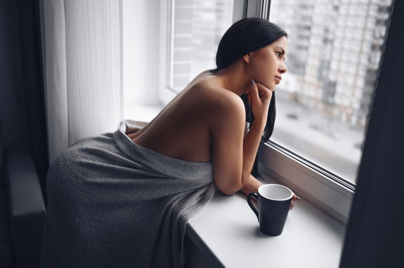 Woman posing in towel by windowsill
