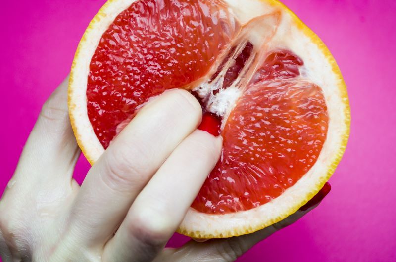 Woman putting fingers in grapefruit