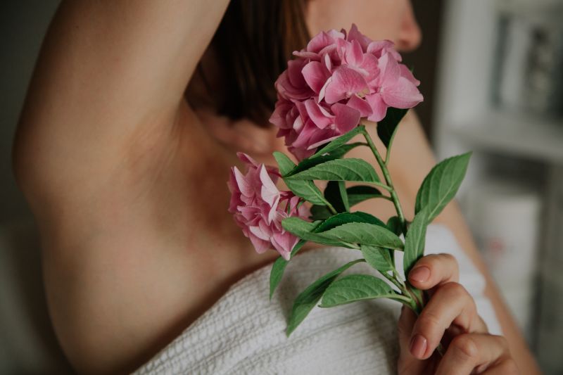 woman raising armpit with flowers