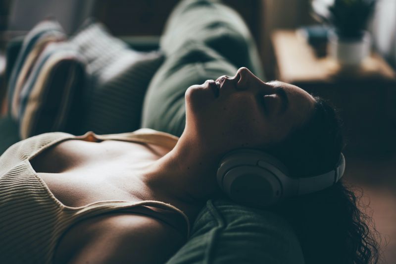 Femme posant sa tête et écoutant de la musique sur un canapé