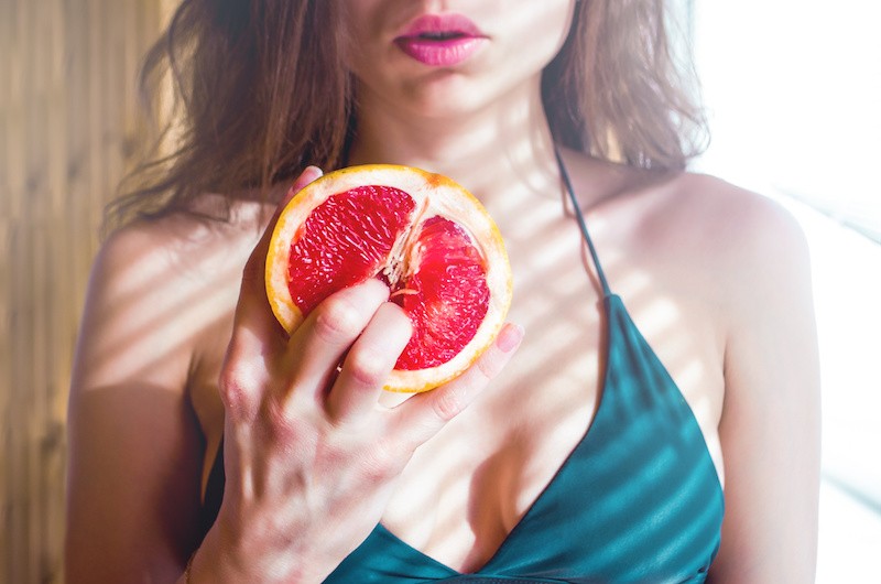 Woman grabbing pomegranate in a sexy posture