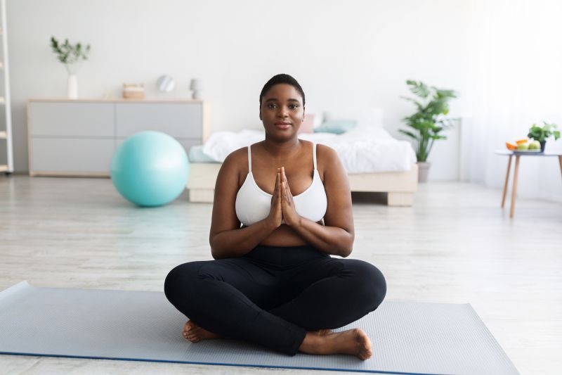 Woman sitting on yoga mat with hands together