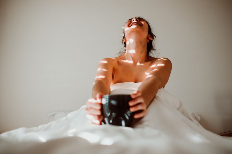 Woman laughing at home in bed with camera