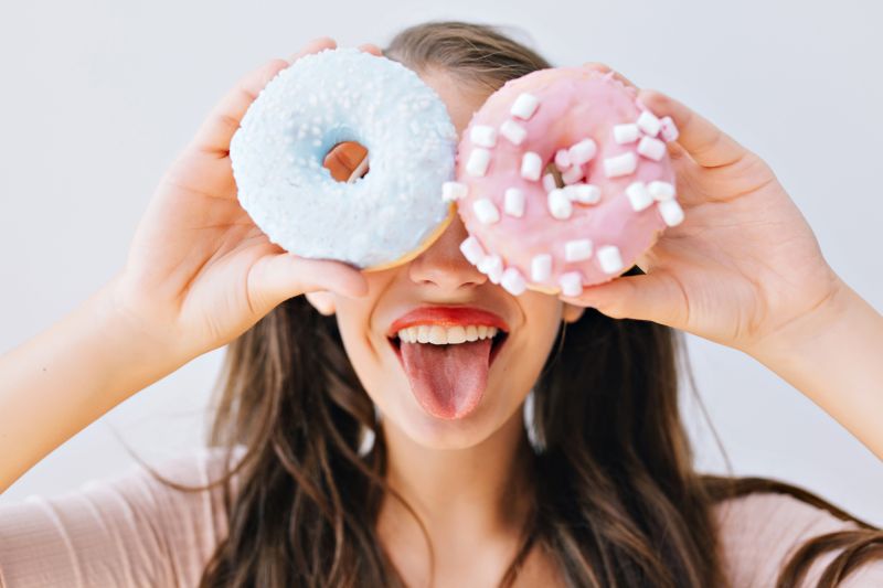 Woman sticking tongue out holding donuts to eyes