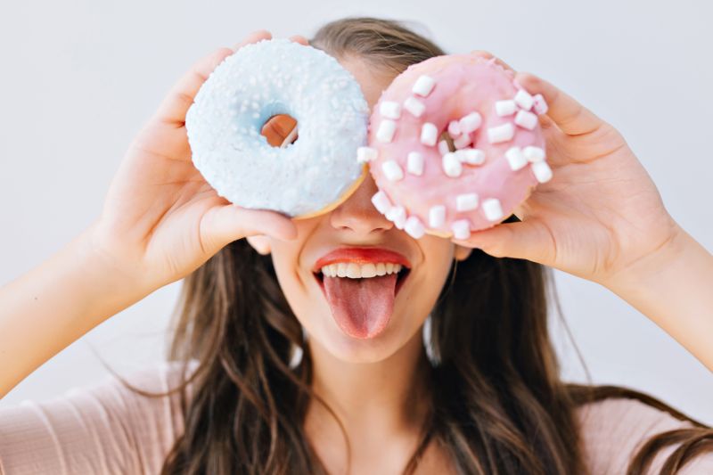 Femme collant la langue tenant des beignets aux yeux