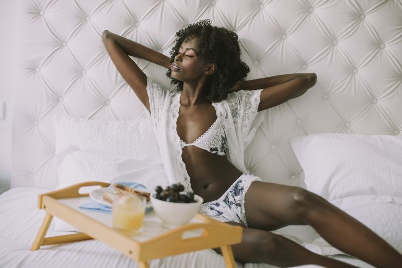 Femme qui s'étend en lingerie blanche avec petit déjeuner au lit