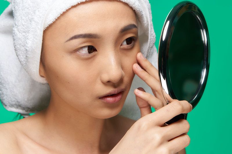 Woman touching her face in mirror