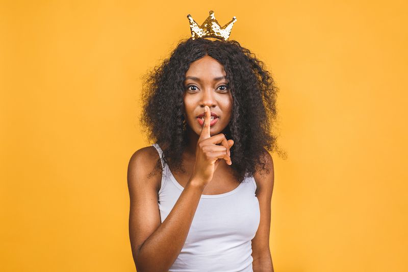 Woman wearing a crown making shh gesture