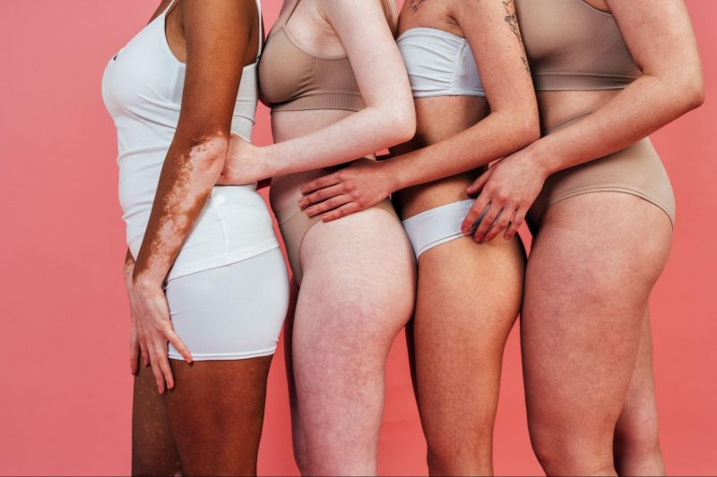 Women hugging in underwear on pink background