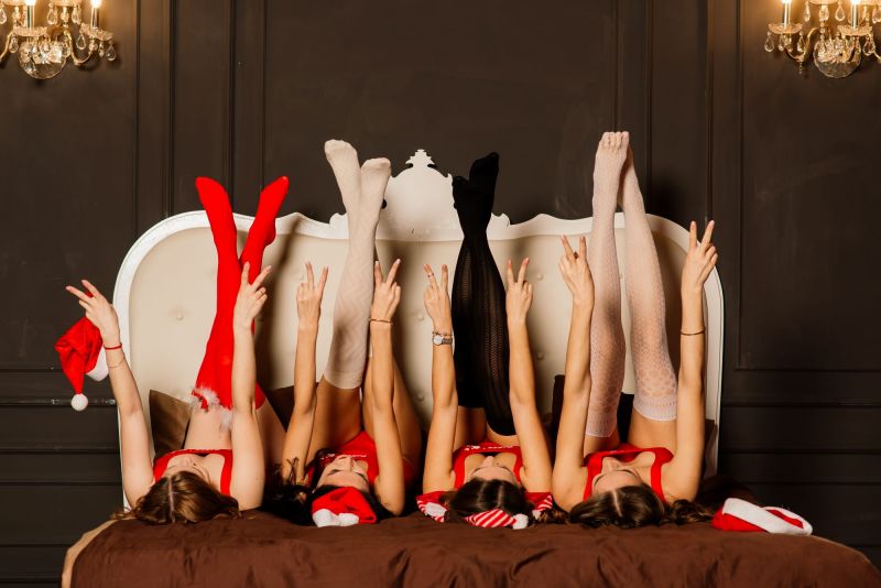 Women in bed with legs up in festive outfits
