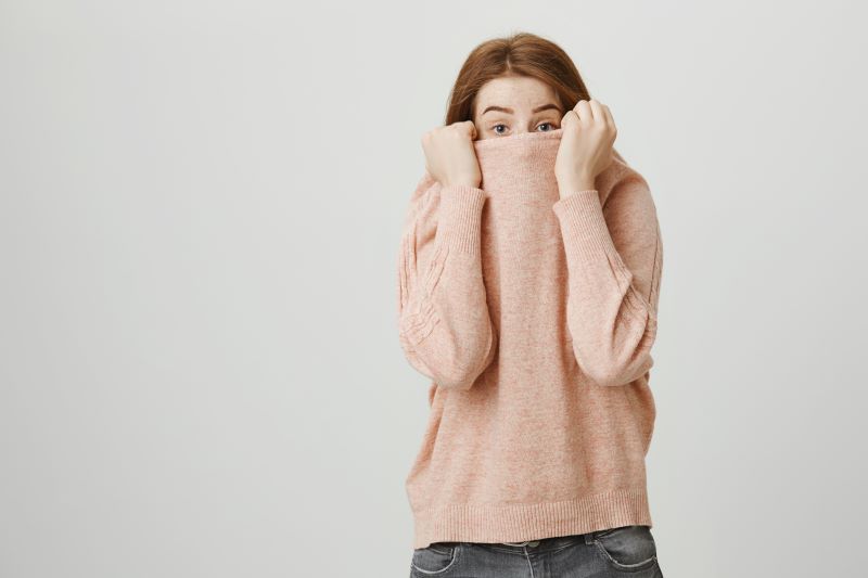 Woman hiding her face in a pink jumper