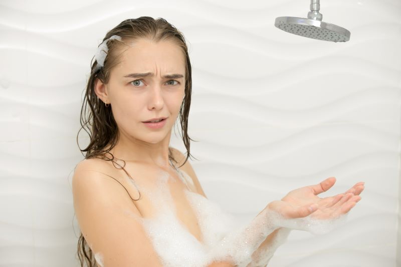 Jeune femme inquiète sous la douche