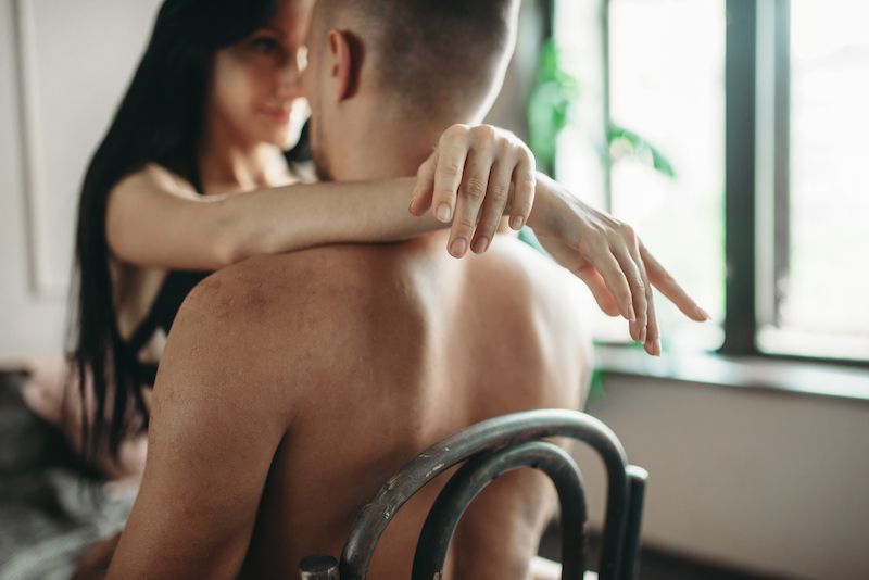 Jeune couple embrassant et faisant l'amour sur une chaise