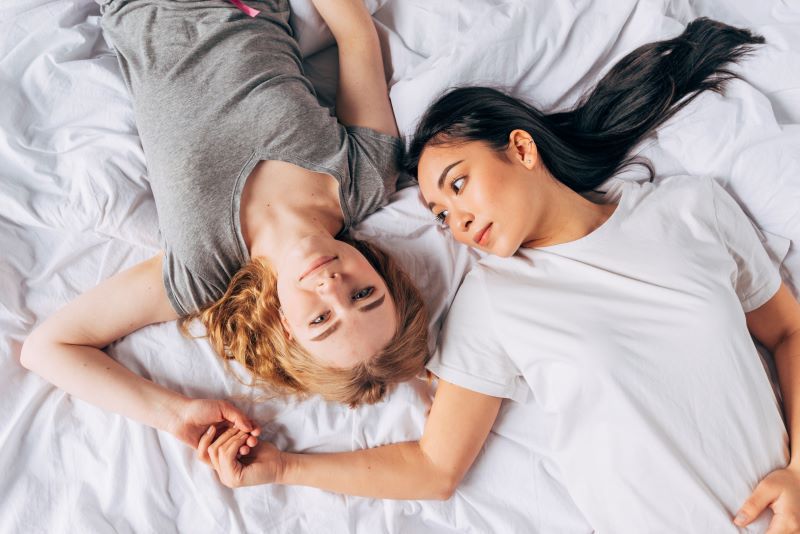 Young couple holding hands in bed