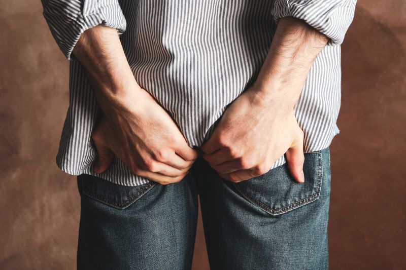 Homme tenant ses fesses à travers un jean