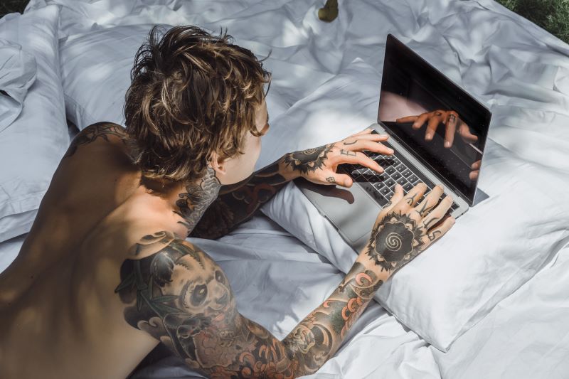 Homme regardant la télévision sur un ordinateur portable au lit