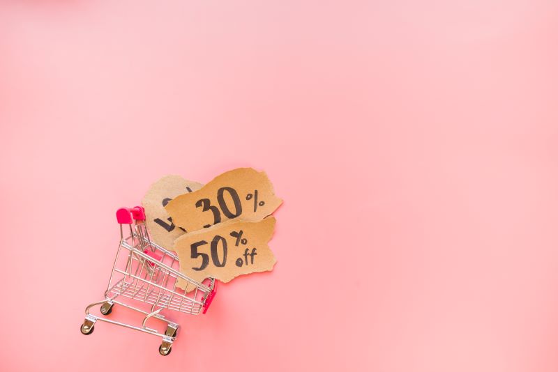 Mini shopping trolley on pink background sale concept
