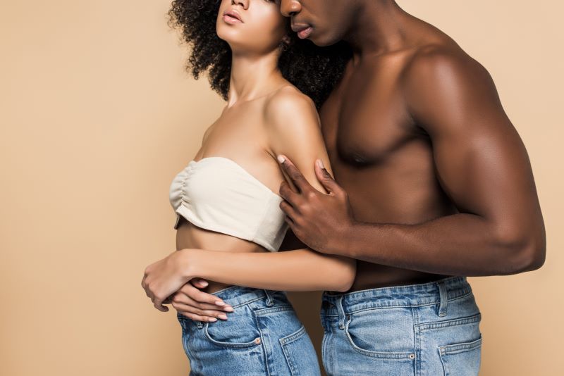 Topless couple embracing on orange background