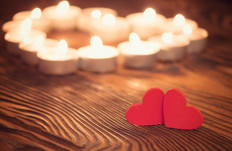 Two love hearts with candles in a heart shape behind them