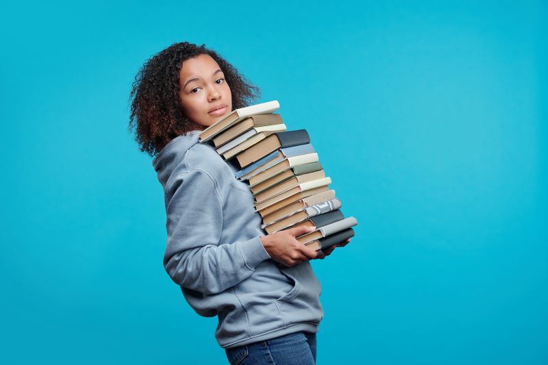 Woman holding big pile of books