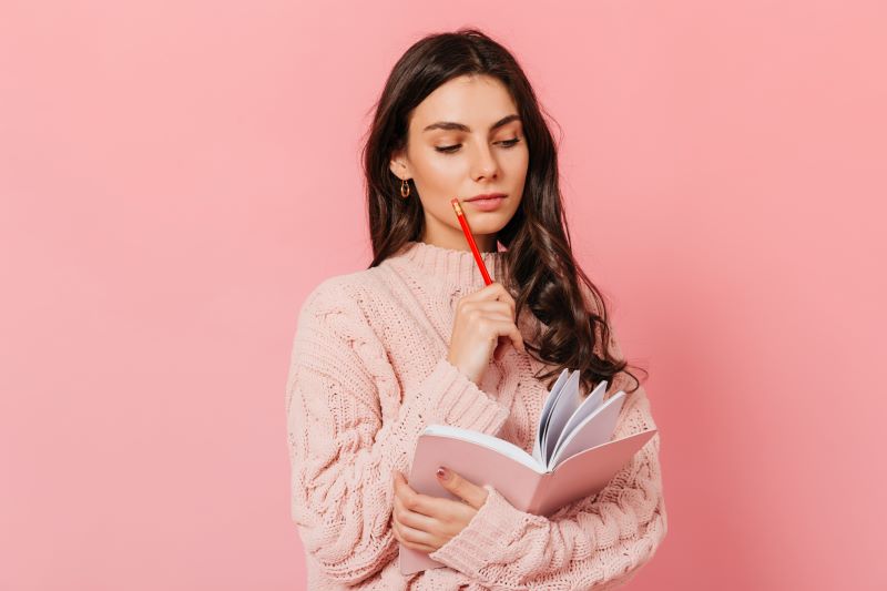 Woman reading and thinking on pink background