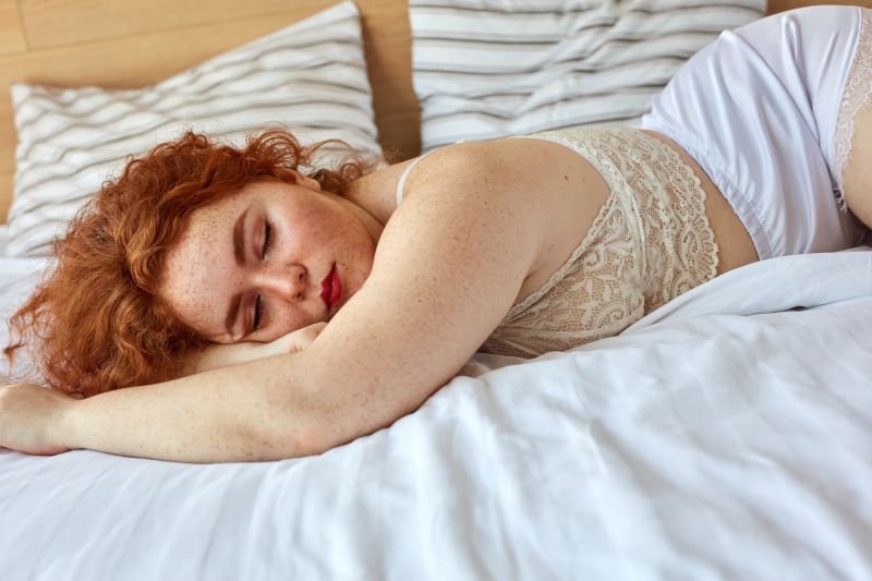 Femme dormant dans son lit en pyjama en dentelle