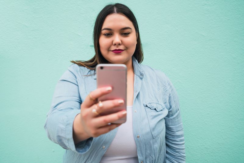 Woman taking selfie on green background